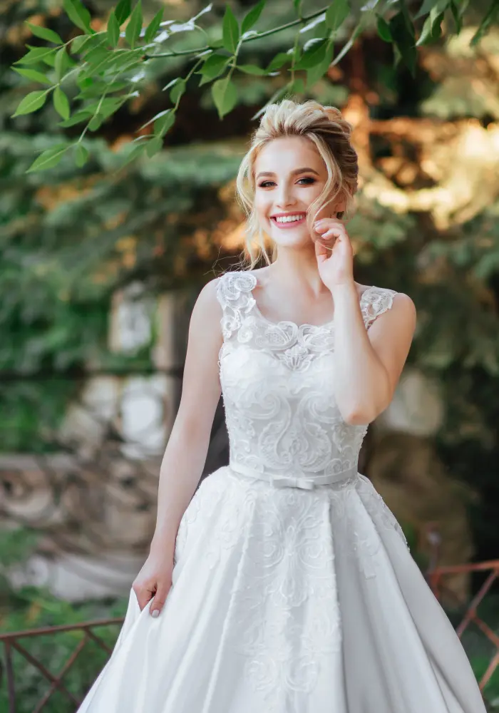 Braut im Spitzenkleid lächelt im Grünen