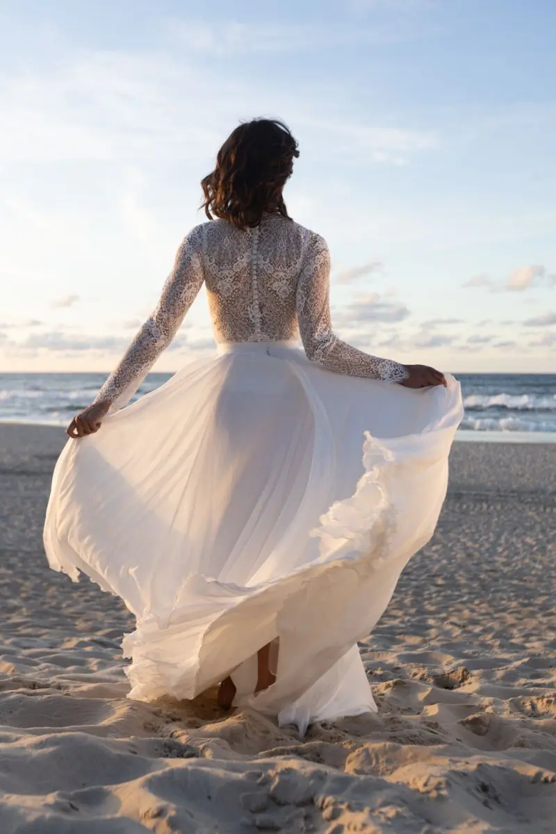Brautkleid Elena mit langen Spitzenärmeln am Strand